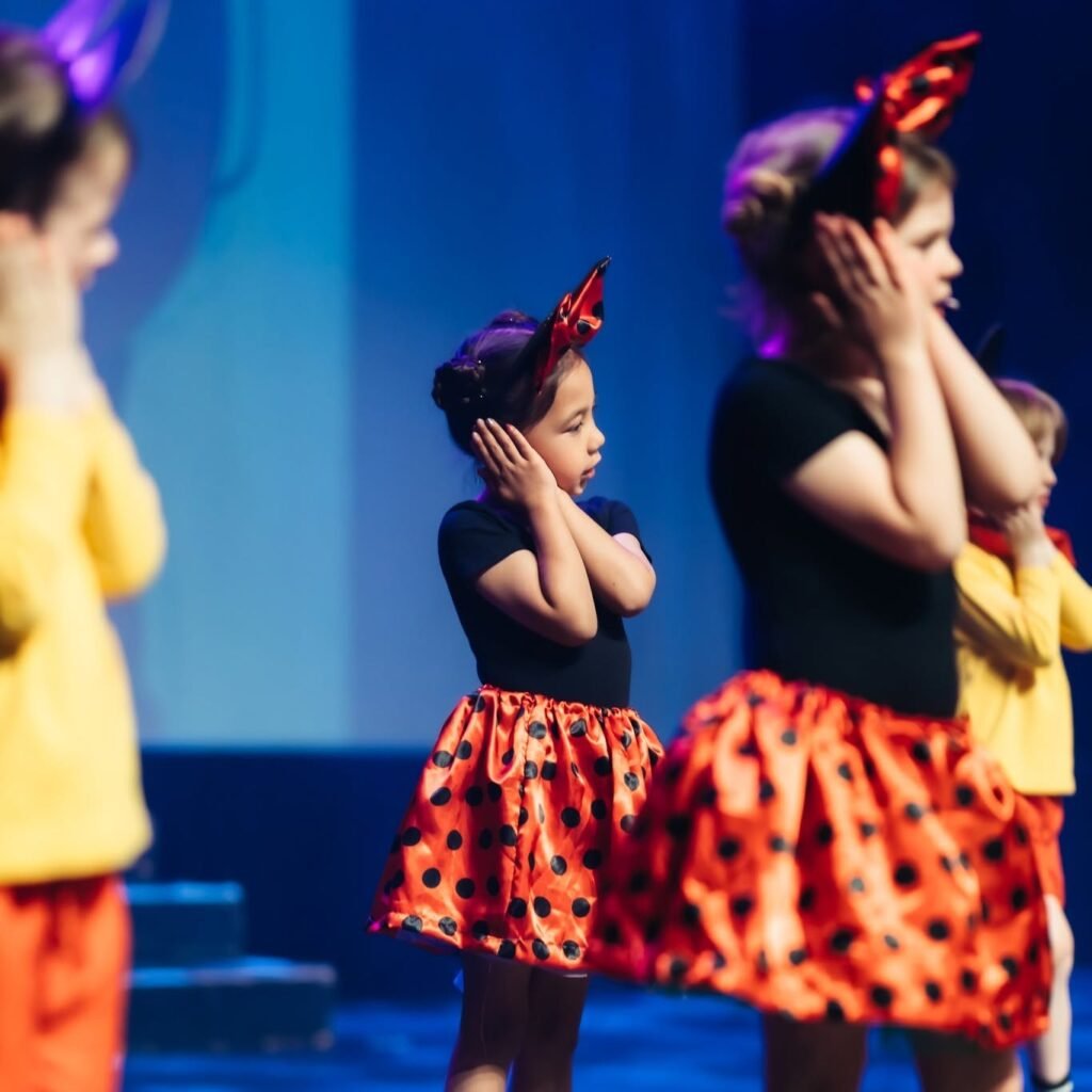 Young performers in colourful costumes dancing on stage.